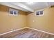 Small basement area with wood-look flooring, window wells for natural light, and neutral walls at 5432 E Bails Dr, Denver, CO 80222