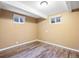 Finished basement area featuring wood-look flooring, neutral walls and two window wells at 5432 E Bails Dr, Denver, CO 80222