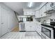 Well-lit kitchen with white cabinets, stainless steel dishwasher and staircase access at 19804 Summerset Ln, Parker, CO 80138