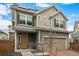Two-story home with neutral-colored siding, solar panels, stone accents, and a tan garage door at 10125 Zeno St, Commerce City, CO 80022