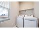 Laundry room with modern washer and dryer units, a window for natural light and overhead shelving at 195 Silver Rock Trl, Castle Rock, CO 80104