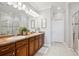 Well-lit bathroom featuring a double vanity, a large mirror, and a glass-enclosed shower for a spa-like experience at 10134 Bluffmont Ln, Lone Tree, CO 80124