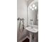 Chic powder room with a pedestal sink, decorative mirror, and bird-themed towel hooks at 10134 Bluffmont Ln, Lone Tree, CO 80124