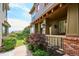 Inviting townhouse entrance with a covered porch, brick foundation, and well-manicured landscaping at 10134 Bluffmont Ln, Lone Tree, CO 80124