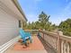 This home features an outdoor deck with blue rocking chairs and views of the tree line at 30313 Arena Dr, Evergreen, CO 80439