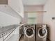Well-lit laundry room with washer, dryer, shelving, and storage cabinets at 9412 La Quinta Way, Lone Tree, CO 80124