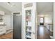 Open pantry storage next to a stainless steel refrigerator, with hallway in the background at 1288 Gambel Oaks Dr, Elizabeth, CO 80107