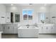Bathroom featuring dual vanities, a soaking tub under a window, black hardware, and white cabinets providing a modern look at 1667 Fox Trotter Pt, Castle Rock, CO 80104