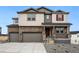 Beautiful two-story home with stone accents, gray siding, a covered porch, and a three-car garage at 1667 Fox Trotter Pt, Castle Rock, CO 80104