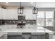 Bright kitchen with white cabinets, a mosaic backsplash, stainless steel appliances and a quartz island at 688 N Bersshine Ct, Watkins, CO 80137