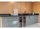 Finished basement wet bar features modern cabinets and counterspace with a sleek black faucet, plus wine refrigerator at 7036 S Apache St, Littleton, CO 80120