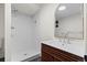Modern bathroom featuring a tiled shower with a rainfall showerhead and a sleek vanity with a wood-slat cabinet at 7036 S Apache St, Littleton, CO 80120