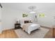 Bright bedroom featuring light hardwood floors, white walls, neutral colors, and two sunny windows at 7036 S Apache St, Littleton, CO 80120