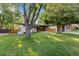 Attractive home with a lush green lawn, mature trees, and contemporary wood and painted brick details at 7036 S Apache St, Littleton, CO 80120