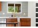Close-up of the kitchen sink featuring modern faucet, white countertops, and stylish backsplash tiles at 7036 S Apache St, Littleton, CO 80120