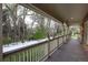 Spacious covered porch with railing offering serene views of the snow-covered backyard and surrounding trees at 1970 Garland St, Lakewood, CO 80215