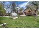 Expansive backyard featuring a lush lawn, mature trees, a charming greenhouse, a spacious deck, and a water feature at 1970 Garland St, Lakewood, CO 80215