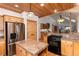 Open kitchen area with wooden cabinets, granite countertops, an island, stainless steel appliances, and wooden floors at 1970 Garland St, Lakewood, CO 80215
