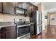 Close-up of kitchen features stainless appliances and dark cabinets, with adjacent door leading to the rest of the house at 21893 E Layton Dr, Aurora, CO 80015