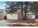 View of the house featuring an attached two-car garage and lush landscaping surrounded by mature trees at 7192 S Vine E Cir, Centennial, CO 80122