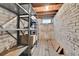 Unfinished storage area with brick walls, wooden floor, and shelving unit at 7011 Grandview Ave, Arvada, CO 80002