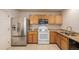 Well-lit kitchen with stainless steel refrigerator, oak cabinets, and granite countertops at 11141 Gaylord St, Northglenn, CO 80233