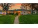 Charming single-story home at sunset with lush green lawn and walkway with landscaped garden at 1935 Oneida St, Denver, CO 80220