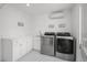 Modern laundry room with stainless steel washer and dryer and custom cabinets with white marble countertop at 6769 E Costilla Cir, Centennial, CO 80112