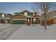 Two-story brick home with green accents and a snow-covered front yard at 6344 E 137Th Ave, Thornton, CO 80602