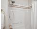 Bathroom featuring a shower over tub with white tiles, brown accent tiles, and gold fixtures at 1281 S Allison St, Lakewood, CO 80232