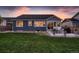 View of home from fenced backyard, featuring a spacious lawn and a concrete patio with patio seating at 11560 Kalispell St, Commerce City, CO 80022