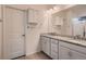 Bright bathroom featuring double sinks with granite countertop, white cabinets, and a framed mirror at 11560 Kalispell St, Commerce City, CO 80022