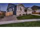 View of a well-maintained home with stone accents, a lush lawn, and a wooden fence along the property line at 11560 Kalispell St, Commerce City, CO 80022