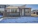 Charming modern home with stone accents, gray trim, and a small fenced yard with snow at 2507 W 69Th Pl, Denver, CO 80221