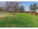 Lush green backyard featuring a mature tree, wooden fencing, and a sloping terrain for outdoor activities at 16533 E Baker Pl, Aurora, CO 80013