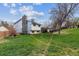 Expansive backyard view featuring lush green grass, a white home with a chimney, and a covered patio at 16533 E Baker Pl, Aurora, CO 80013