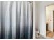 Clean bathroom featuring a shower with an ombre curtain, a white toilet, and access to other parts of the house at 16533 E Baker Pl, Aurora, CO 80013
