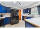 Spacious kitchen with blue cabinets, white countertops, stainless steel appliances, and tile flooring at 16533 E Baker Pl, Aurora, CO 80013