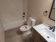 Bright bathroom featuring a white tub, toilet, gray tile floor, and a vanity with a white countertop and dark hardware at 9322 Jackson St, Thornton, CO 80229