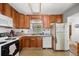 An open concept kitchen with wood cabinets, stainless steel sink, white appliances, and natural light at 2742 S Xanadu Way, Aurora, CO 80014