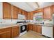 A classic kitchen with wood cabinets, white appliances, and a sink below the window with natural light at 2742 S Xanadu Way, Aurora, CO 80014