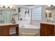 Bathroom featuring a luxurious soaking tub, dual sinks, decorative tile, and a decorative glass-blocked window at 14075 Turnberry Ct, Broomfield, CO 80023