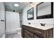 Modern bathroom featuring a double sink vanity, stylish mirrors, and tiled shower with a skylight at 7704 Newland St, Arvada, CO 80003