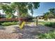 Wooden playground set with swings and slide on pebble ground at 7704 Newland St, Arvada, CO 80003