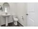 Clean half bathroom featuring a pedestal sink, toilet, and a white door at 17706 Cherokee St, Broomfield, CO 80023