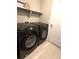 A laundry room featuring front loading Samsung washer and dryer, storage shelf, and white door at 4680 Copeland Loop # 203, Highlands Ranch, CO 80126