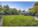 Large backyard with lush grass, mature trees, and a covered patio area at 5857 S Logan Ct, Centennial, CO 80121