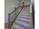 Carpeted staircase with wood railing and black iron balusters leading to the upper level of the home at 16858 Greyhawk Dr, Monument, CO 80132