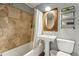 Bathroom featuring a pedestal sink, tiled shower with a bathtub, an oval mirror, and shelving at 13905 W 21St Ave, Golden, CO 80401