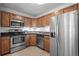 Well-lit kitchen with stainless steel appliances, wooden cabinets, and dark countertops at 8603 E Dry Creek Rd # 214, Englewood, CO 80112